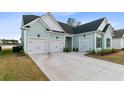 Three car garage featuring carriage doors, black hardware and well manicured landscaping at 552 Marsh Cv Cir, Summerville, SC 29486