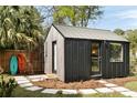 Modern backyard house with sleek gray siding and a metal roof, surrounded by greenery and stepping stones at 639 Bridlewood Ln, Mount Pleasant, SC 29464
