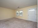 Neutral carpeted living room with large window and a white front door, offering a bright and welcoming space at 7079 N Kenwood Dr, North Charleston, SC 29406