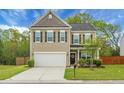 Charming two-story home featuring a well-manicured lawn, neutral siding, black shutters, and an attached two-car garage at 7818 Expedition Dr, North Charleston, SC 29420