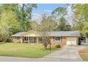 Charming single-story brick home with a well-manicured lawn, inviting porch swing and an attached garage at 103 Arbor Rd, Summerville, SC 29485