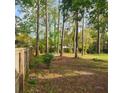 Large backyard featuring mature trees, a wooden fence, a fire pit, and plenty of space for outdoor activities at 129 Bramwell Dr, Summerville, SC 29485
