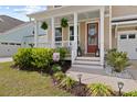 Inviting front porch featuring manicured shrubs, beautiful hanging plants, and decorative accents at 154 Calm Water Way, Summerville, SC 29486