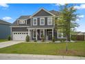 Two-story home with attached garage, manicured lawn, and a tree on the front yard, showcasing suburban living at 180 Basket Grass Ln, Summerville, SC 29486