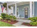 Inviting front porch with white columns, Adirondack chairs, and well-manicured landscaping at 2383 Lenwick Hall Ln, Johns Island, SC 29455
