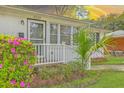 A close up of the front porch of a brick home, featuring azaleas, a palm tree, and white railing at 5337 Hartford Cir, North Charleston, SC 29405