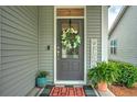 Charming front door with a wreath, a welcome sign, potted plants, and a gray exterior at 603 Dunswell Dr, Summerville, SC 29486