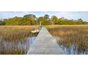 A wooden dock extends over the water, leading to a boat under a blue sky at 630 Cain Dr, Mount Pleasant, SC 29464