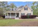 Charming home featuring a cozy front porch, dormer windows, and lush landscaping at 8618 Mcchune Ct, North Charleston, SC 29420
