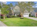 Beautiful two-story home with brick and siding exterior, complemented by lush landscaping at 9447 Harroway Rd, Summerville, SC 29485