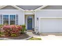 Inviting entrance showcasing a blue front door, a wreath, and blooming bushes by the front window at 9703 Mosgrove Ave, Ladson, SC 29456