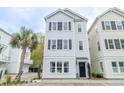 Charming three-story home with white siding, black shutters, and a well-maintained yard at 975 Warrick Oaks Ln, Mount Pleasant, SC 29464
