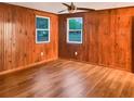 Bedroom with wood paneled walls, new hardwood floors, and bright windows overlooking the yard at 1085 Russellville Rd, Saint Stephen, SC 29479
