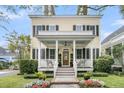 Inviting two-story home featuring a covered porch, black shutters, and beautiful landscaping at 12 Leeann Ln, Mount Pleasant, SC 29464