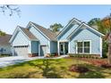 Charming single-story home featuring light blue siding, gray garage doors and a well-manicured lawn at 2036 Yaupon Way, Johns Island, SC 29455