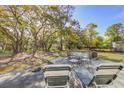 Spacious backyard with a patio, seating, and mature trees providing shade at 322 Lantana Dr, Charleston, SC 29407