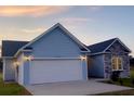 A two-car garage is connected to the house with light blue siding, and stone accent wall at 3292 N Highway 52, Saint Stephen, SC 29479