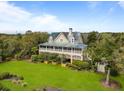 Beautiful exterior view of home with a metal roof, spacious porch, lush landscaping and mature trees at 377 Lofton Ct, McClellanville, SC 29458