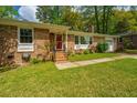 Charming brick home with a vibrant red door, complemented by flowering plants and a well-kept lawn at 6018 Ridgecrest Ave, Hanahan, SC 29410