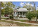 Charming light blue two-story home with a landscaped yard and a quaint white picket fence along a green lawn at 803 S Main St, Summerville, SC 29483