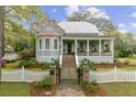 Charming light blue two-story home with a landscaped yard, brick gate posts, and a quaint white picket fence at 803 S Main St, Summerville, SC 29483