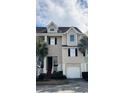 Inviting townhome exterior with a one car garage, complemented by lush landscaping and palm trees at 155 Winding River Dr, Johns Island, SC 29455