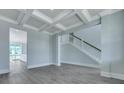 Spacious living room with coffered ceiling, view of dining area, staircase with white railing, and hardwood floors at 203 Bilge Rd, Ridgeville, SC 29472