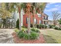 Side view of a brick home featuring mature landscaping, palm trees, and a charming front porch at 1185 Out Of Bounds Dr, Summerville, SC 29485