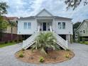 Beautiful two-story home with a palm tree in the yard, complemented by gray gravel and white stairs at 3510 Myrtle St, Edisto Island, SC 29438
