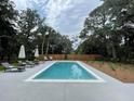 Outdoor swimming pool featuring several lounge chairs and umbrellas surrounded by a wooden privacy fence at 3510 Myrtle St, Edisto Island, SC 29438