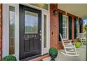 Elegant front door featuring decorative glass, gold accents, and the house number, framed by brick and a rocking chair at 3584 Somerset Hills Ct, Mount Pleasant, SC 29466