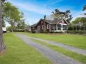 Quaint red home with a screened-in porch, long driveway, and spacious yard surrounded by trees at 402 N Hickory Street St, Summerville, SC 29483