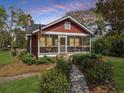 Inviting red home with a screened-in porch, well-kept landscaping, and charming curb appeal at 402 N Hickory Street St, Summerville, SC 29483