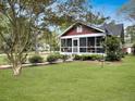 Well-maintained red home features a screened-in porch, lush lawn, and vibrant landscaping at 402 N Hickory Street St, Summerville, SC 29483