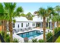 Backyard oasis with pool, lounge chairs, umbrellas, palm trees, and privacy fence at 4310 Stonehouse Cir, Awendaw, SC 29429
