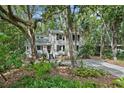 Inviting home with a covered porch nestled among mature trees and lush greenery at 597 Oyster Rake Dr, Kiawah Island, SC 29455