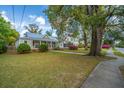 Inviting home featuring a well-manicured lawn and charming curb appeal amidst mature trees and blue skies at 617 Hampton St, Walterboro, SC 29488