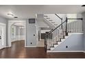 Inviting entryway with dark wood floors, staircase with white spindles, and a view into the dining room at 8499 Falling Leaf Ln, North Charleston, SC 29420