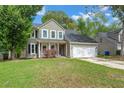 Charming two-story home with light green siding, a well-manicured lawn, and an attached two-car garage at 8499 Falling Leaf Ln, North Charleston, SC 29420