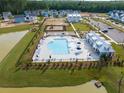 Aerial view of a community pool with sun loungers, umbrellas, playground, and gathering area near the pool at 1014 Marsh Harrier Dr # Cc3-1-5, Ravenel, SC 29470