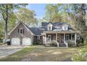 Inviting home boasts a brick facade, covered porch, dormer windows, and attached two-car garage at 109 Dan Miler Ln, Summerville, SC 29483
