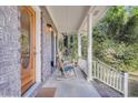 Cozy front porch featuring a brick base, rocking chairs, and a wooden front door with glass inlay at 109 Dan Miler Ln, Summerville, SC 29483