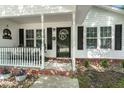 Close-up of the inviting front porch, complete with a decorative door, black shutters, and stone-accented landscaping at 1306 Markley Ct, Moncks Corner, SC 29461