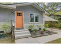 Close-up of front entrance featuring an orange door, white brick accents, and beautifully landscaped garden beds at 1531 Seacroft Rd, James Island, SC 29412