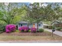 View of charming home featuring beautiful azaleas, light-gray siding, orange door, and covered parking area at 1531 Seacroft Rd, James Island, SC 29412