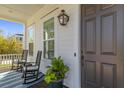 Inviting front porch featuring rocking chairs, a stylish rug, and charming details like an outdoor lantern at 1555 Willtown St, Daniel Island, SC 29492
