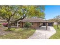 Charming brick home with mature trees, covered carport, and well-manicured lawn on a sunny day at 1673 Mcclain St, Charleston, SC 29407