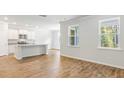 Open-concept living space with natural light, hardwood floors, and a view of the modern kitchen at 348 Dickerson Ln, Lincolnville, SC 29485