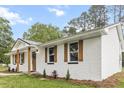 Side view of a renovated brick home showcasing new windows, wood shutters, and landscaped garden at 463 E Main Street, Harleyville, SC 29448