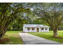 Quaint brick home with new metal roof, windows, and shutters, framed by mature trees and a long driveway at 463 E Main Street, Harleyville, SC 29448